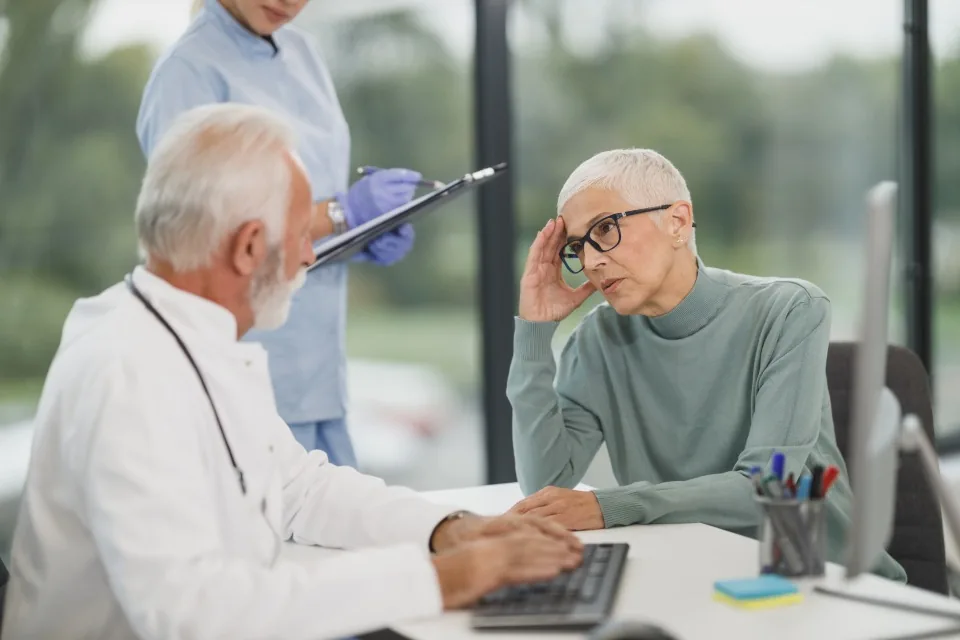A doctor at a desk talking with a patient in a clinic